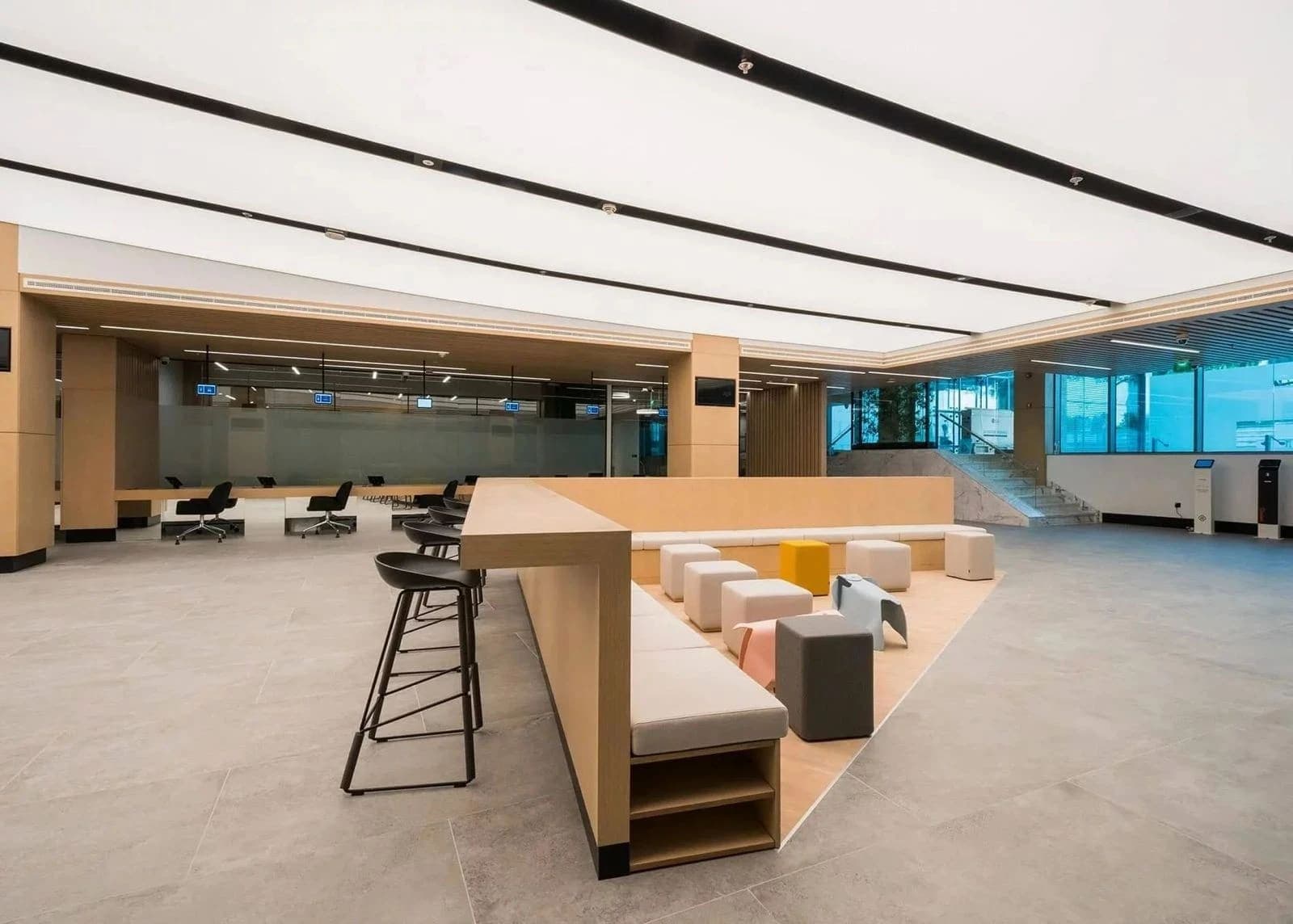 Large open-plan space under a bright backlit stretch ceiling divided by slim black lines