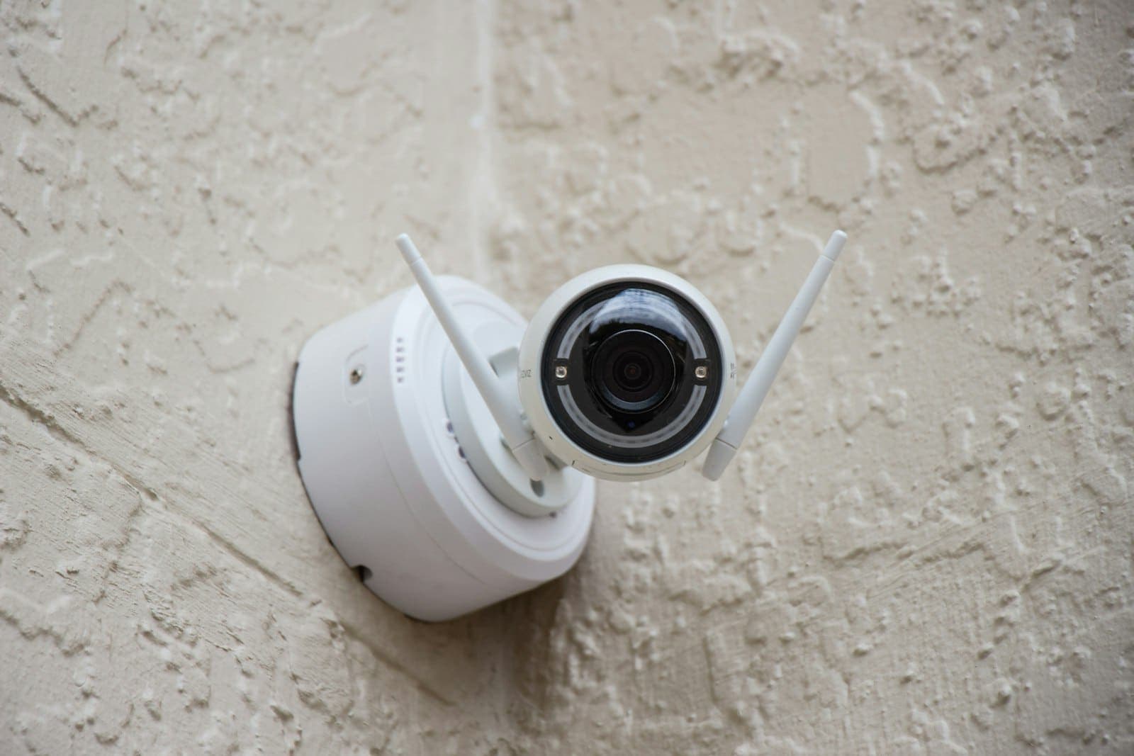White Wi-Fi security camera mounted on a textured wall