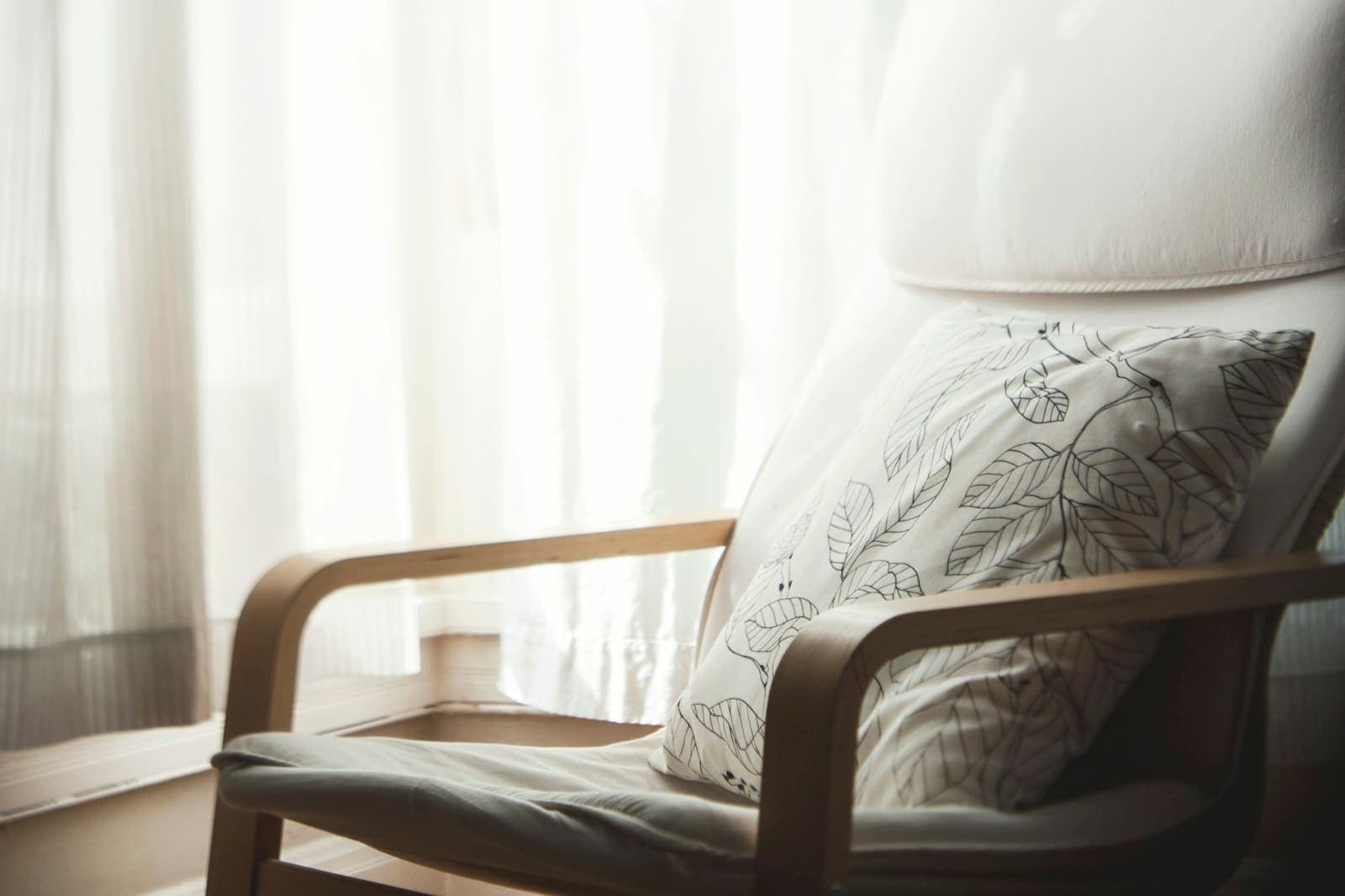 Armchair beside softly lit sheer curtains
