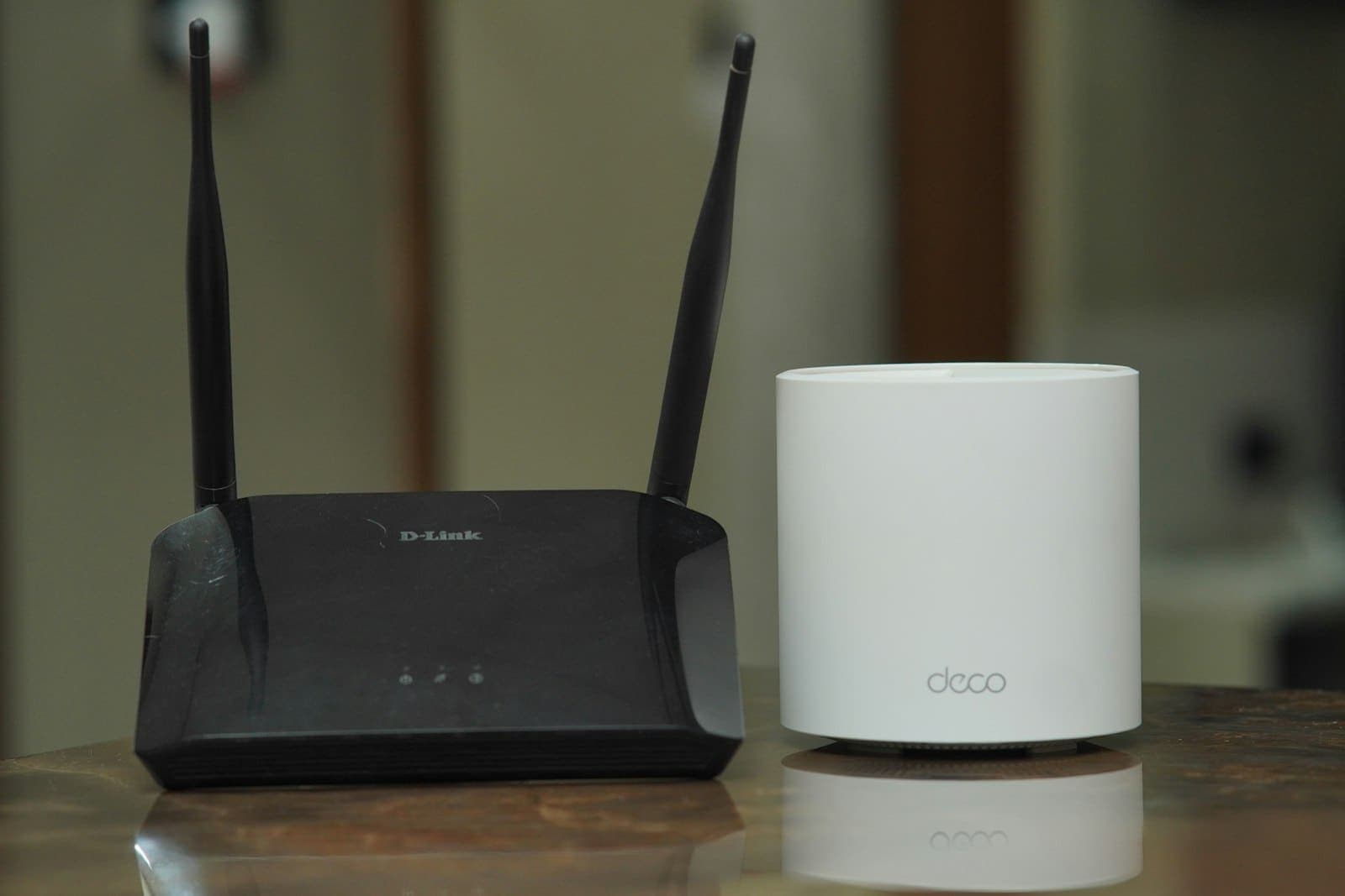 Wi-Fi router beside a mesh Wi-Fi unit on a table